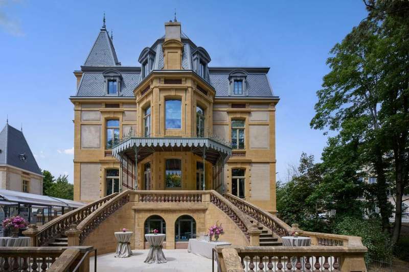 The golden-stone facade of Villa Pétrusse, with its turrets and double staircase.
